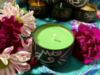 a green candle is sitting on a table next to a bouquet of flowers